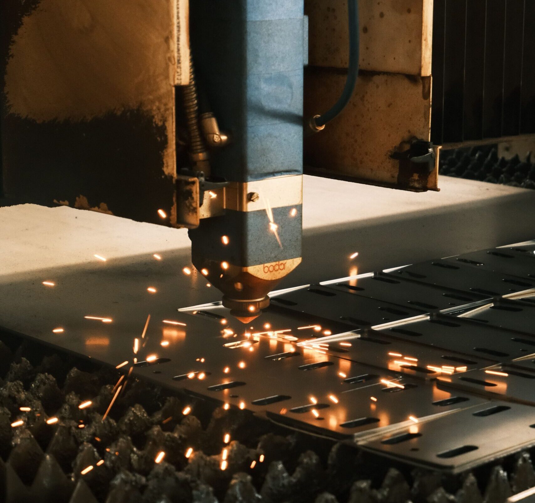 Close-up of a laser cutter in action, producing sparks in a modern manufacturing facility.